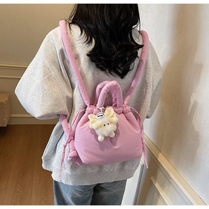 Detail of pink quilted puffer mini backpack with cute white plush charm on model