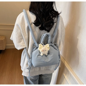 Light blue quilted drawstring backpack with plush monster pendant shown on model back