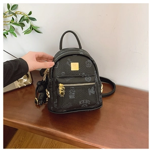 Detailed macro view of black faux leather mini backpack with golden bear charm and logo