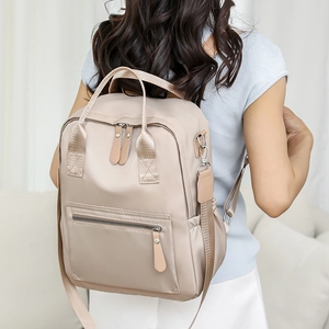 Détail du sac à dos en nylon beige avec texture satinée lisse et poche latérale pratique
