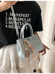 Sac fourre-tout en cuir verni bleu clair avec fermoir argenté et breloque ours sur modèle