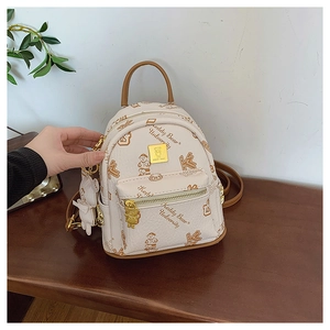 Detail of cream PU leather mini backpack featuring cartoon bear print and golden hardware