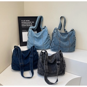 Detail showing four shades of washed denim crossbody bags with adjustable straps
