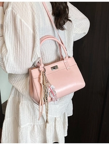 Sac fourre-tout élégant en cuir rose avec détails argentés et breloques sur robe blanche