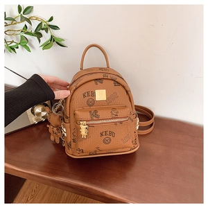 Detail of a brown leather mini backpack with bear motifs and gold hardware on a wooden table