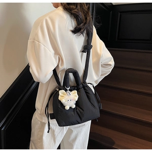 Detailed shot of black quilted bubble bucket bag with a cute white plush monster charm