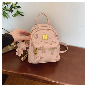Close-up of pink mini backpack with bear pattern, gold hardware and matching charm