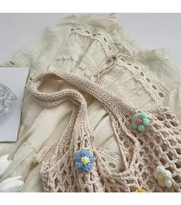 Dettaglio della borsa in maglia con fiori colorati all'uncinetto e trama a rete