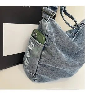 Detail of washed denim crossbody bag showing durable side pocket and vintage distressed texture