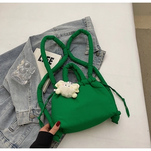 Macro detail of puffy green nylon bucket bag with plush white kitten charm and thick strap