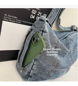 Detail of denim crossbody bag showing side zipper pocket with a phone for capacity