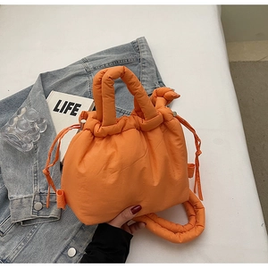 Detailed view of orange quilted puffer bucket bag with drawstring and padded handle
