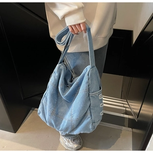 Detail of light blue patchwork denim tote showing distressed side pocket and texture
