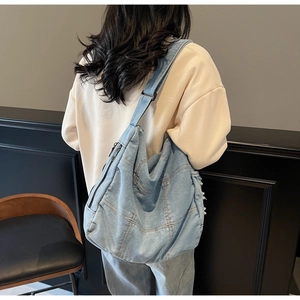 Detailed back view of a light blue denim tote bag worn by a model in a minimalist setting