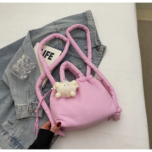 Detailed shot of pink quilted puffy handbag with cute plush doll charm and soft handles