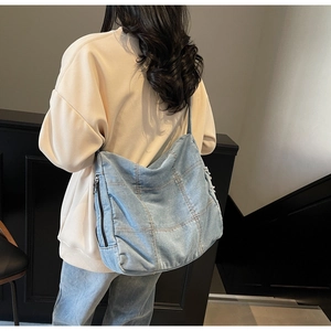 Detail of light blue denim tote bag with patchwork design and side zipper pocket
