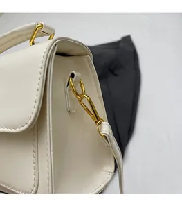 Close-up of golden lobster clasp and D-ring hardware on cream faux leather handbag