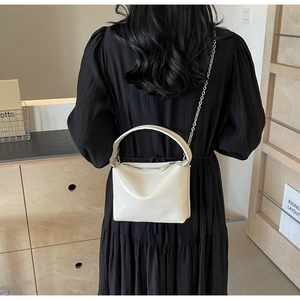 Detail shot of the cream-white faux leather handbag with silver chain and zipper closure