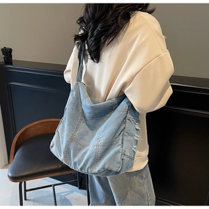 Detail of light blue denim tote bag with frayed edges and large patch stitching texture