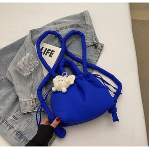 Detail of bright blue quilted down bag with soft fluffy kitten charm and thick straps