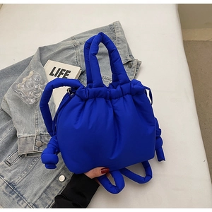 Detail showing royal blue quilted puffy handbag with drawstring closure and knotted handle