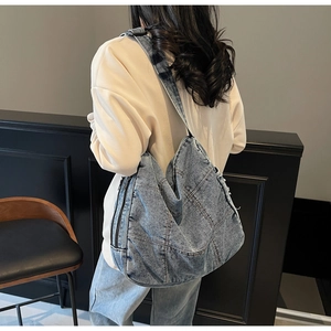 Rear view of a model wearing the large blue denim tote bag with quilted stitching detail