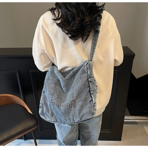 Detail of vintage denim tote bag showing distressed edges and stitching on casual shoulder strap