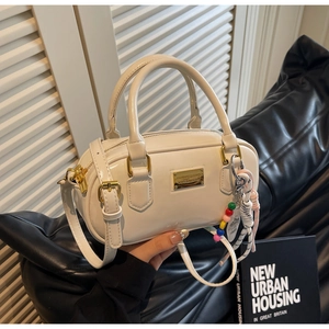 Détail du sac Boston en cuir verni crème avec ferrures dorées et breloque en perles