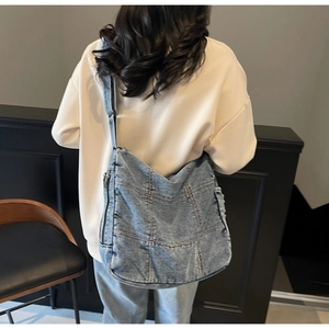 Macro detail of the denim stitching and metallic zipper on this vintage crossbody tote bag
