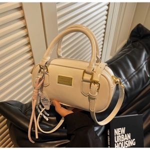 Détail du sac bowling blanc crème avec boucles dorées et accessoire de poignée tressé