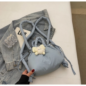 Close-up of light blue quilted bucket backpack with drawstring and plush charm detail