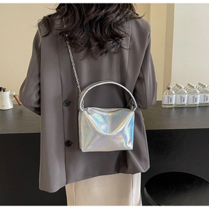 Close-up of a silver holographic crossbody bag with metal chain strap and top handle