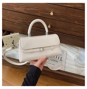 Close-up of beige leather crossbody bag with silver buckle and adjustable shoulder strap