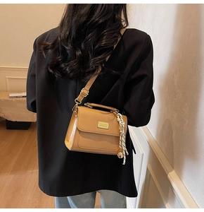 Detail of camel square crossbody bag featuring gold metal plate and knot pendant