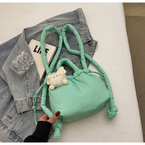 Detail of mint green quilted puffer bucket bag featuring a soft knotted shoulder strap