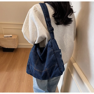 Detailed view of the dark denim crossbody bag showing patchwork stitching and a side pocket