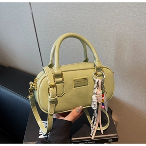 Gros plan du sac Boston vert pistache avec plaque dorée sur une boîte cadeau de luxe