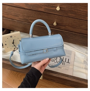 Close-up of a light blue rectangular crossbody bag with a silver buckle and top handle