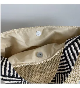 Detail of silver magnetic buckle and woven strap on a summer straw tote bag
