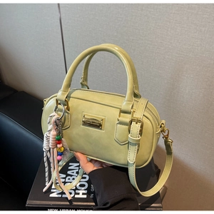 Détail du mini sac Boston vert clair avec plaque dorée et accessoire charme coloré