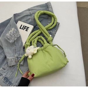 Detail of light green quilted puffy bag with cute white rabbit charm on denim jacket