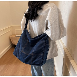 Detail of deep blue denim tote featuring contrast stitching and vintage frayed edges