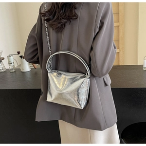 Close-up of metallic silver crossbody bag with chain strap and handle on a model