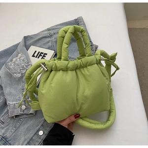 Close-up of avocado green puffer bucket bag with drawstring and padded handle detail
