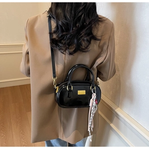 Vue arrière du mannequin portant un sac bowling noir verni avec foulard rose et chaîne dorée