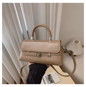 Close-up of a glossy tan leather crossbody bag featuring a classic buckle and metal details
