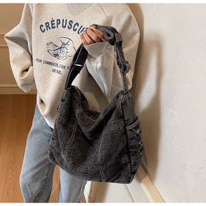 Detail of vintage black denim tote bag with white contrast stitching and adjustable strap