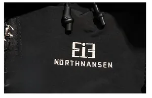 Détail du logo brodé sur un sac à dos de sport noir avec fermeture éclair et tissu résistant