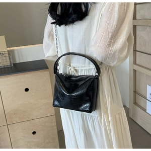 Chic black wrinkled leather handbag with silver chain shown on model in minimalist setting