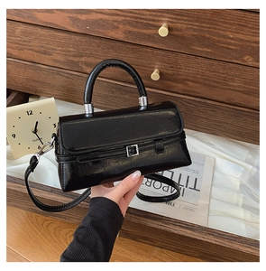 Detailed close-up of a black leather handbag with a silver buckle and retro lychee texture